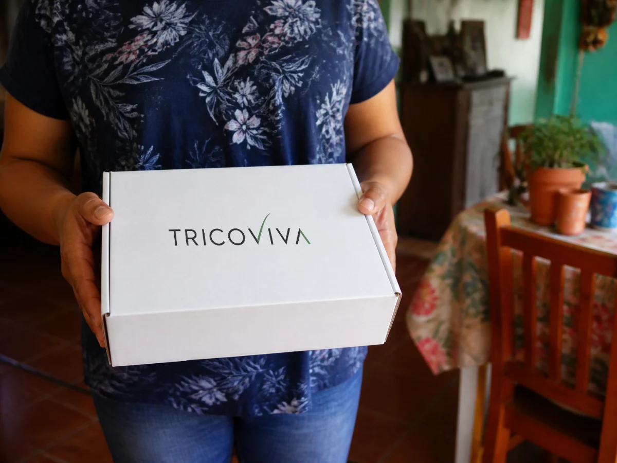 Manos sosteniendo la caja del kit capilar TricoViva