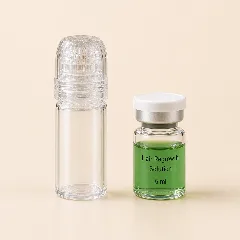 La microaguja con su tapa junto a una ampolleta de sérum verde